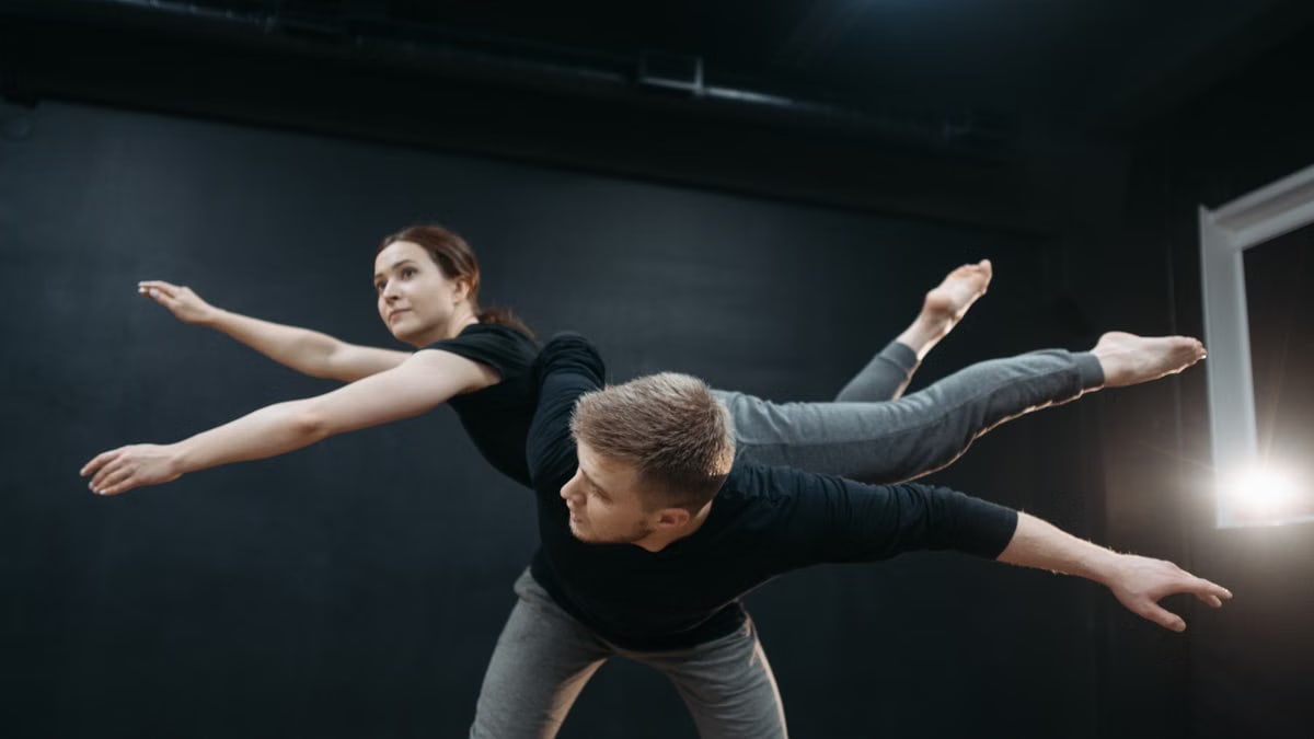 A couple gracefully performs contemporary dance in a studio, showcasing passion and flexibility.